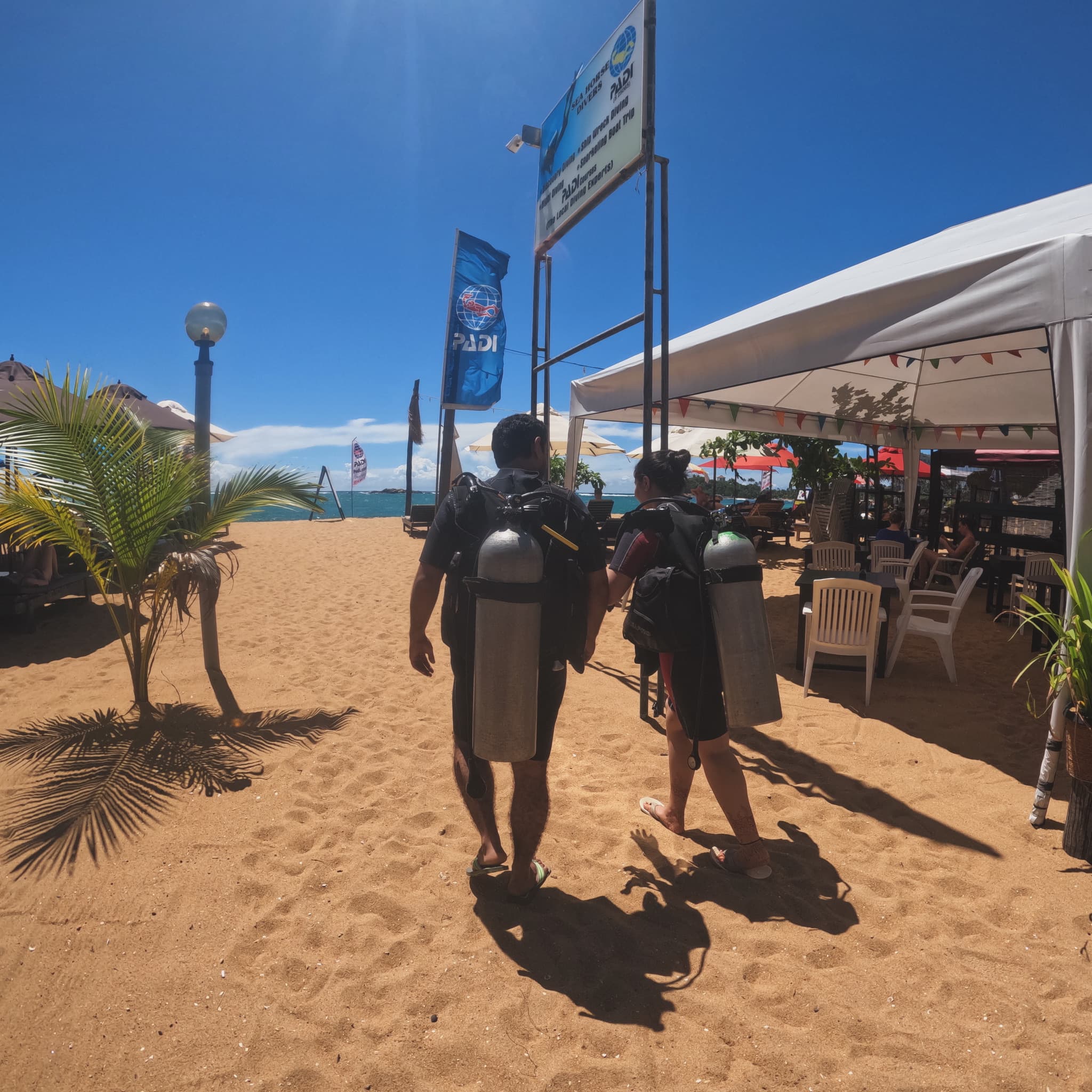 Divers carrying their tanks across the sand at Unawatuna Beach