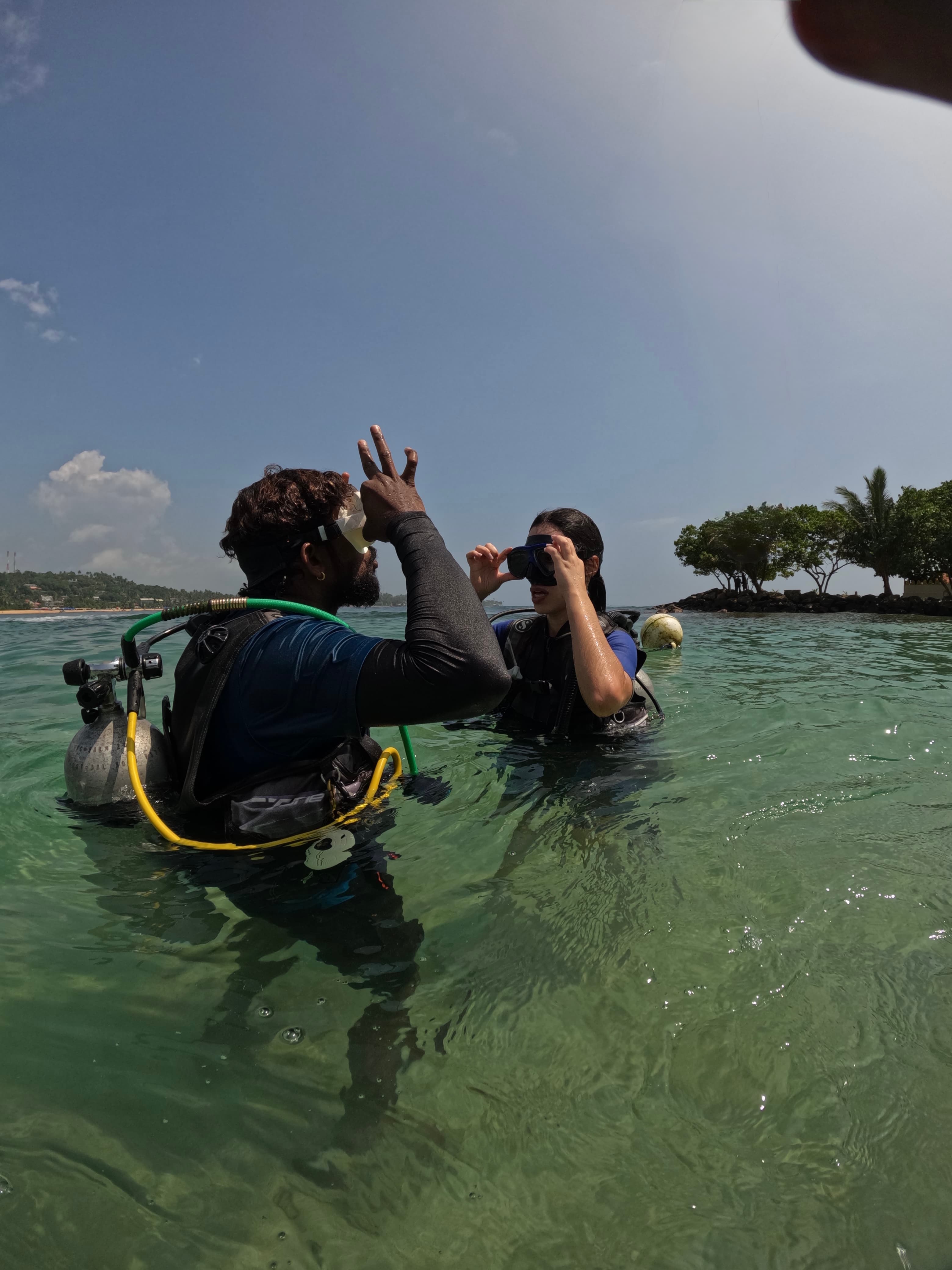 Instructor helping a student diver with their mask in the shallows at Unawatuna